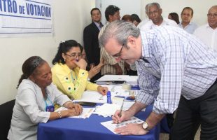 Luis Abinader firma documentación mientras vota