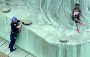 Una mujer escala la estatua de la Libertad en protesta por la política migratoria